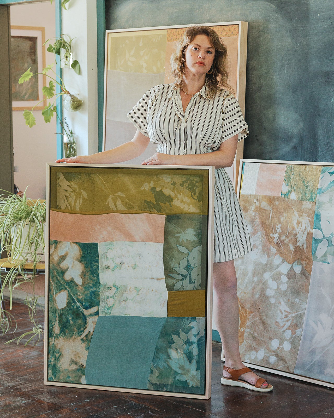 Woman holding a framed abstract artwork in an art gallery setting